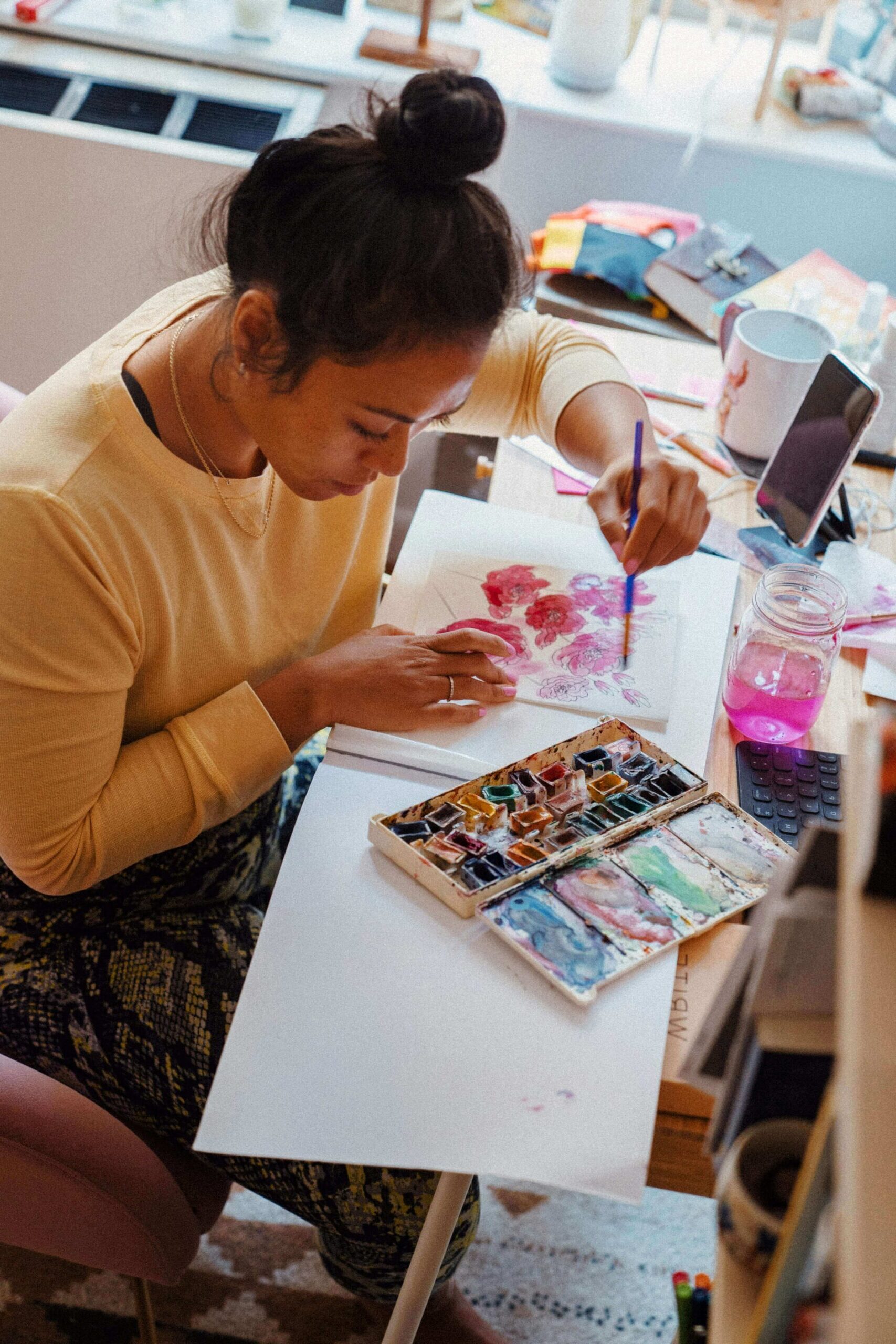 Woman seated at a table creating expressive artwork with oil pastels and mixed media materials during an art therapy session