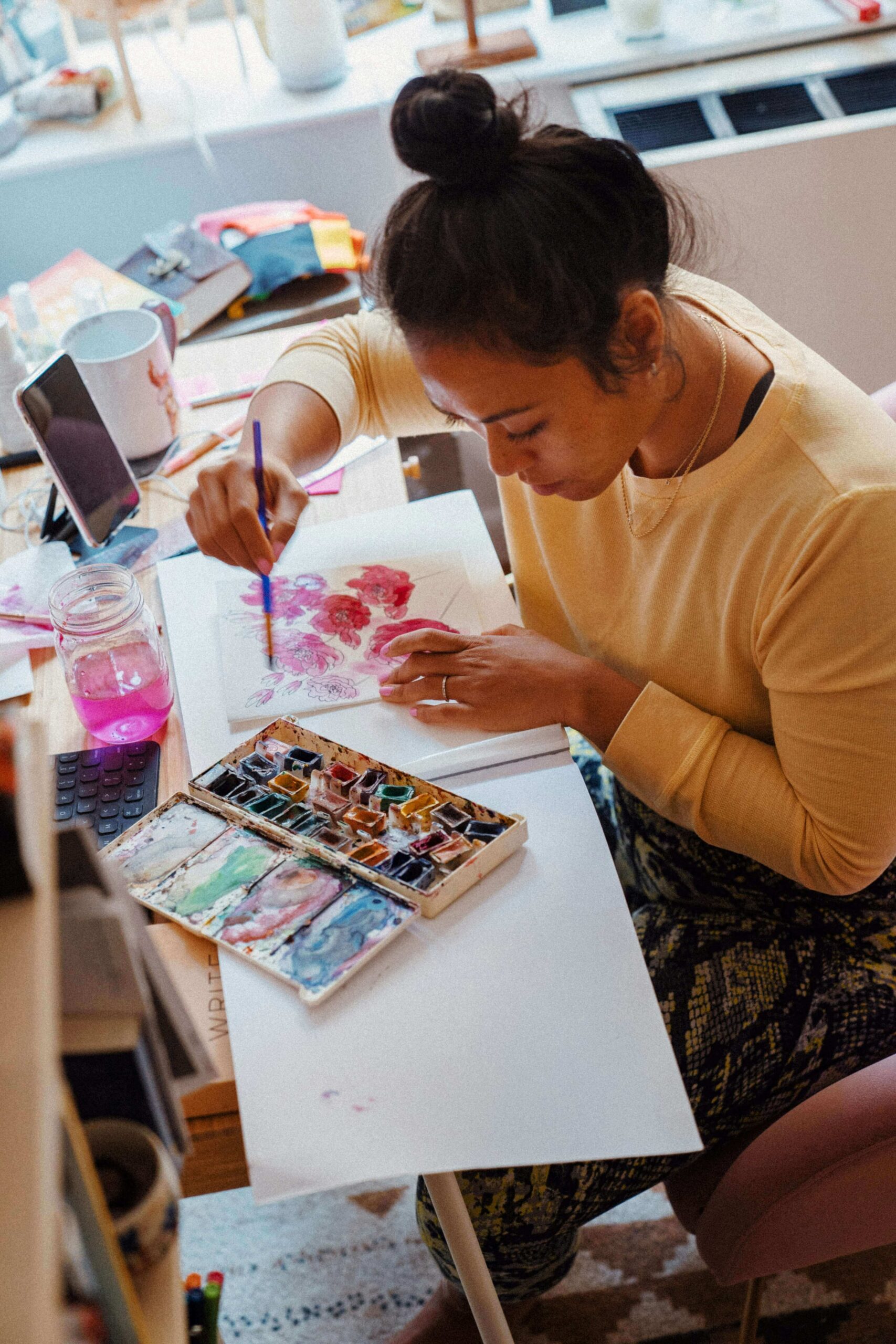 Woman seated at a table creating expressive artwork with oil pastels and mixed media materials during an art therapy session